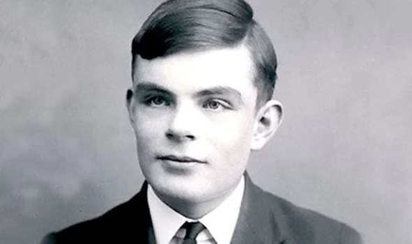 Black and white portrait photograph of a young man with dark side-parted hair, wearing a dark jacket, white collar and striped tie, looking toward the right of the frame.