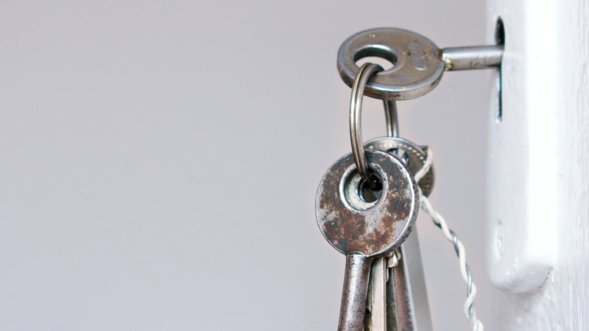 A ring of keys hangs from a key turned in the lock of a white door.