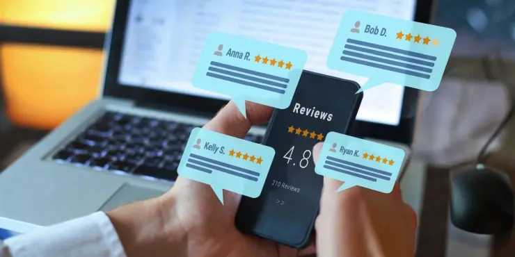 Hands holding a phone showing a Reviews screen with a 4.8 star rating and 210 reviews, surrounded by floating speech bubbles with names and star ratings, in front of a laptop.