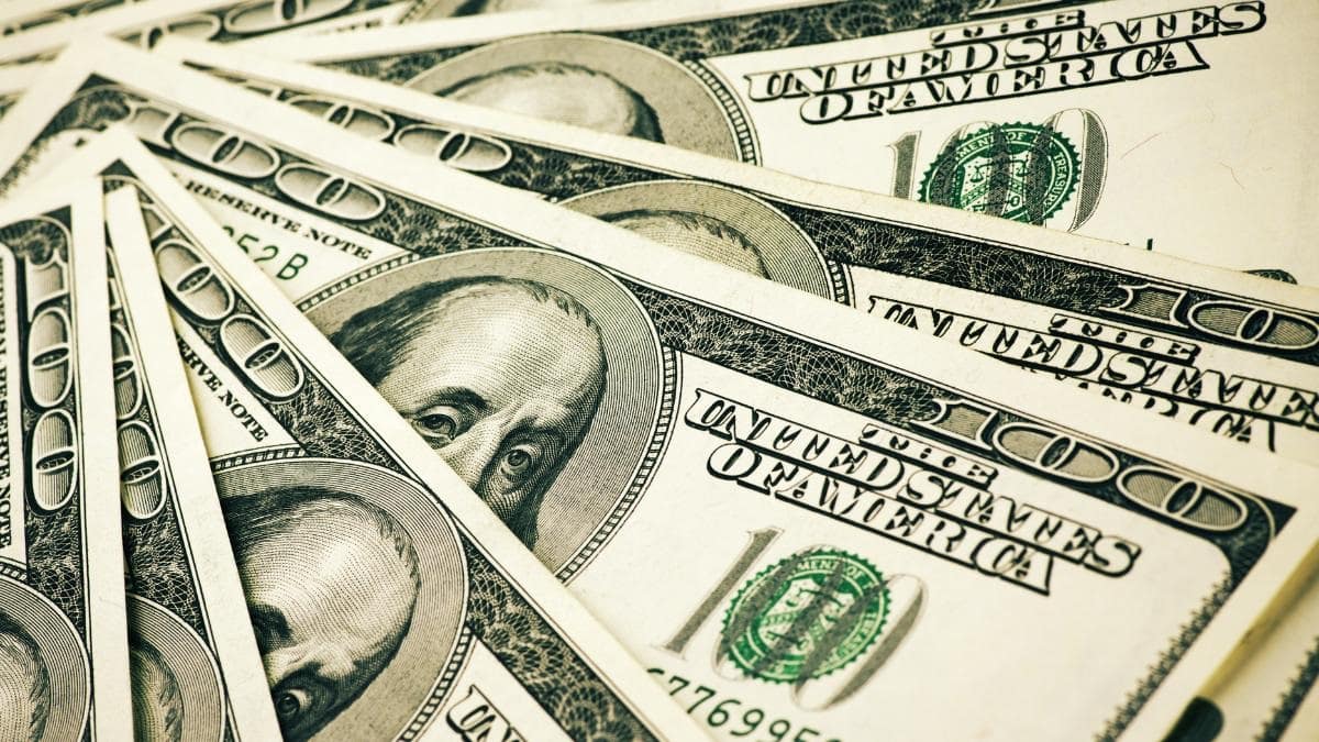 A close-up fan of overlapping United States one hundred dollar bills showing the Benjamin Franklin portrait.